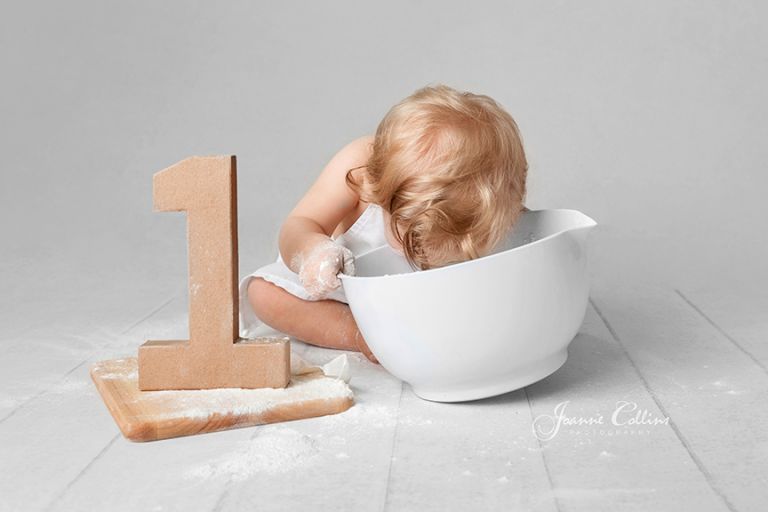 first year birthday photo session, baby girl with her head in the mixing bowl