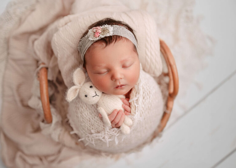 Newborn baby photographer near me. Baby girl cuddling a bunny and the colours are lovely oatmeal.